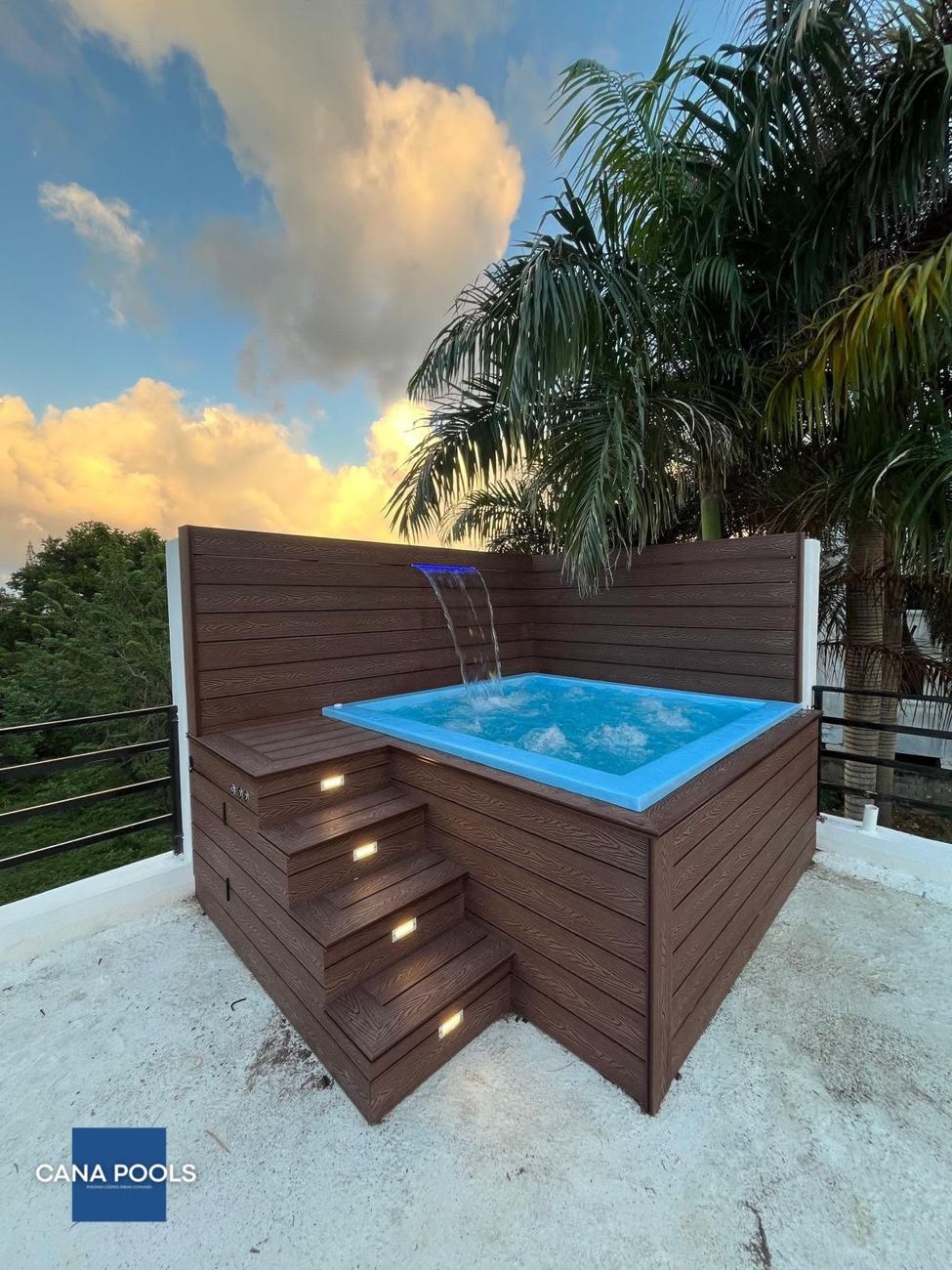 Jacuzzi con cascada iluminada y deck de madera